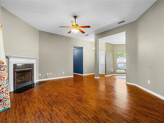 Unfurnished living room featuring wood finished floors, ceiling fan, visible vents, and a tile fireplace