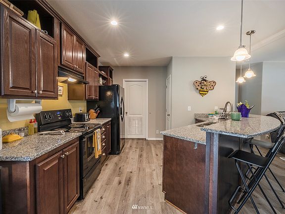 Open kitchen with granite slab counters, pantry and kitchen island with breakfast bar.
