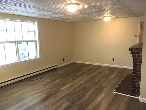 The living room features a gorgeous full southern-facing window, new flooring, new ceiling, new lights, and a non-working fireplace.