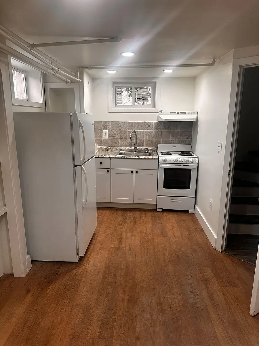 Efficient kitchen with full-size refrigerator, range, and sink, plus a tiled backsplash and durable flooring. - Forrest Ave
