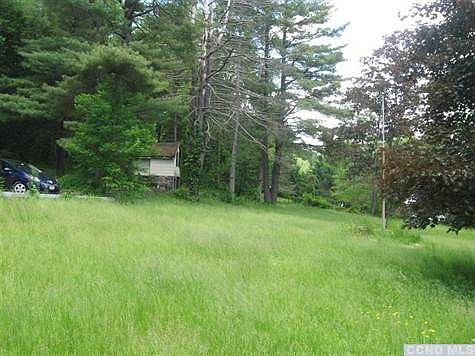 open fields surround this house with mature woods