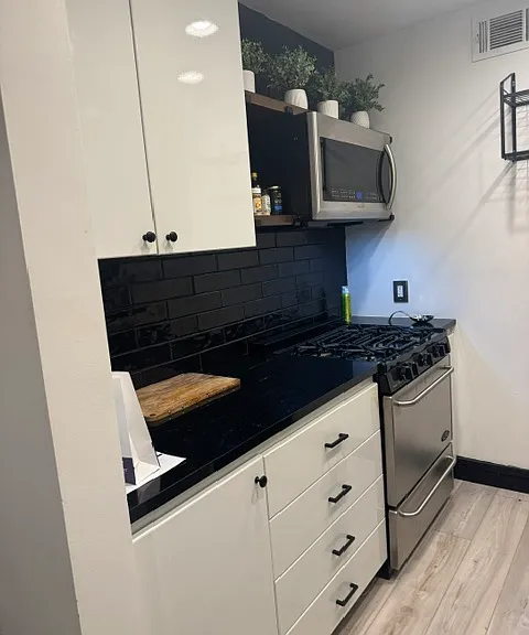 Black and white color palette in the kitchen. Stainless steel appliances. Built-in microwave.