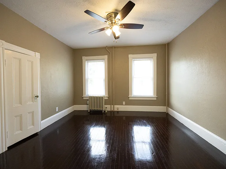 Spacious bedroom with ceiling fan and hardwood floors