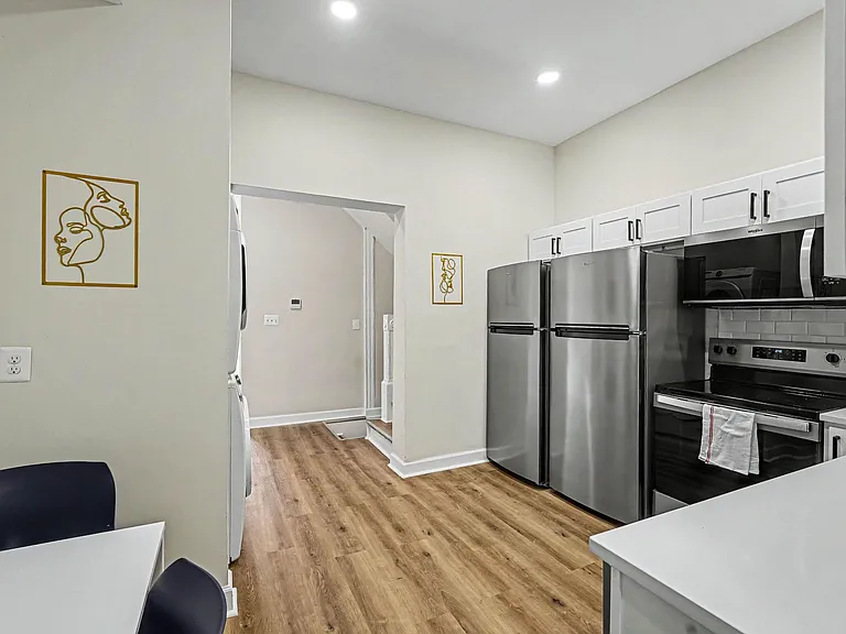 Well-equipped kitchen with stainless steel appliances, ample white cabinetry, and durable wood-look flooring for easy upkeep.