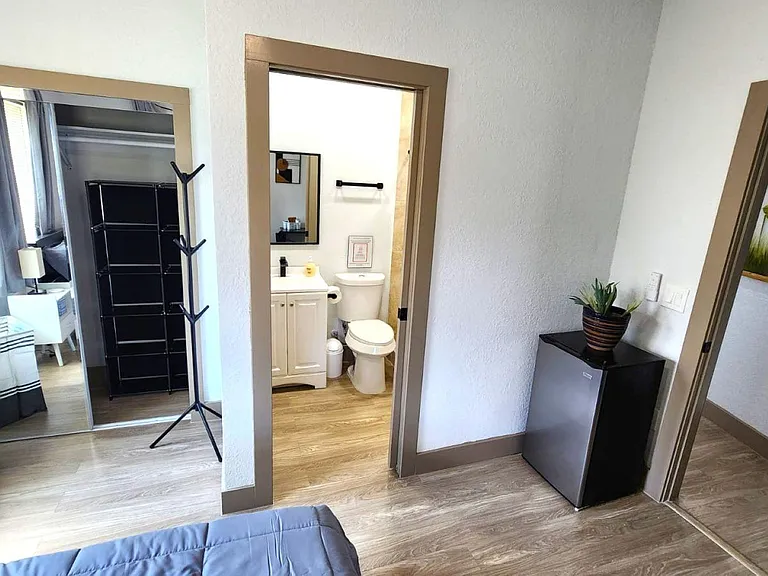 Private bedroom suite with closet storage, mini fridge area, and convenient access to an adjacent full bathroom.