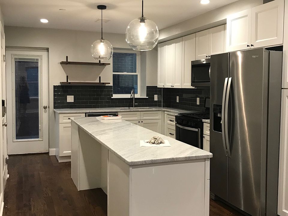 Kitchen with quartzite counter tops, stainless steel appliances (including dishwasher), open shelving. Door to deck.