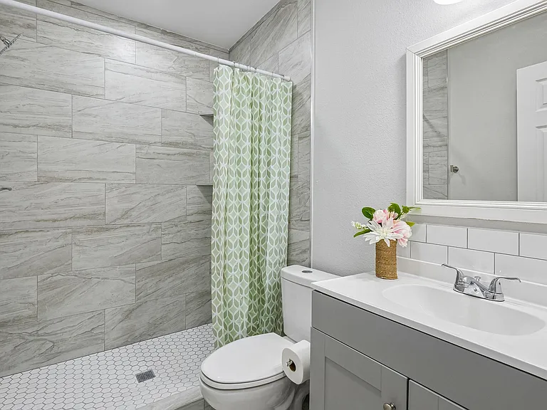 Updated bathroom with a walk-in tile shower, built-in niches, and a vanity with ample counter space and large mirror.