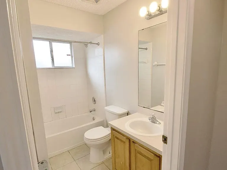 Full bathroom with tub/shower combo, wide vanity with storage, and a window for ventilation and natural light.