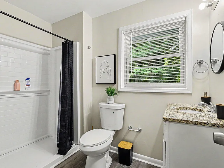 Full bathroom with tub/shower combo, subway tile surround, granite-look vanity, and window with blinds for ventilation.