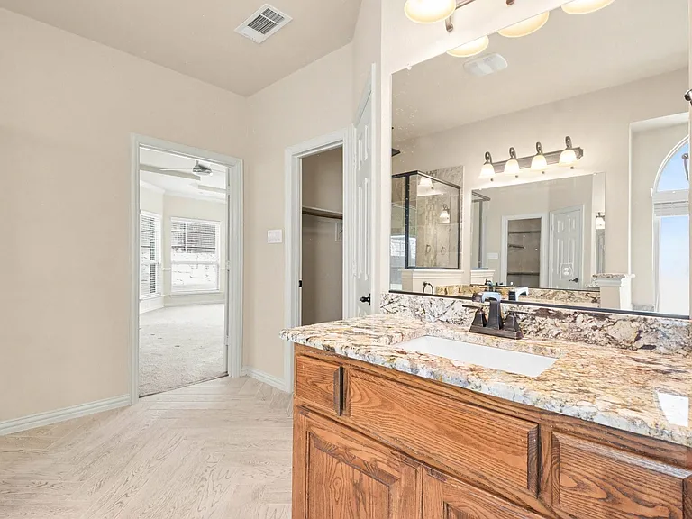 Bathroom vanity featuring a single-basin sink, bronze-finish faucet, and a patterned stone countertop