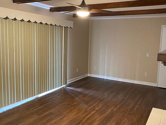 Den with sliding glass door and ceiling fan.