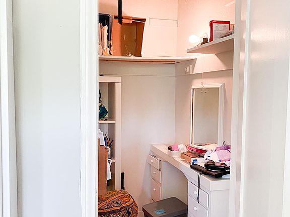 messy walk-in closet with vanity table. currently not used for clothes