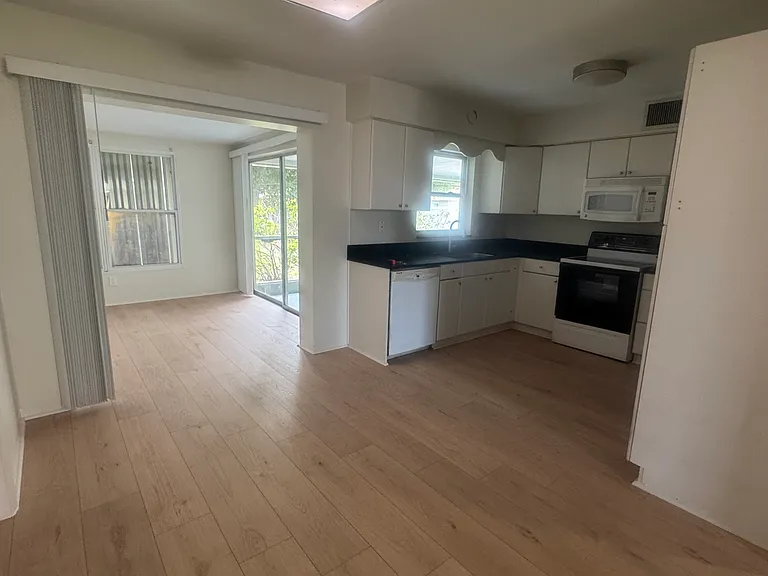 view from dining area into kitchen and bonus room and lanai.