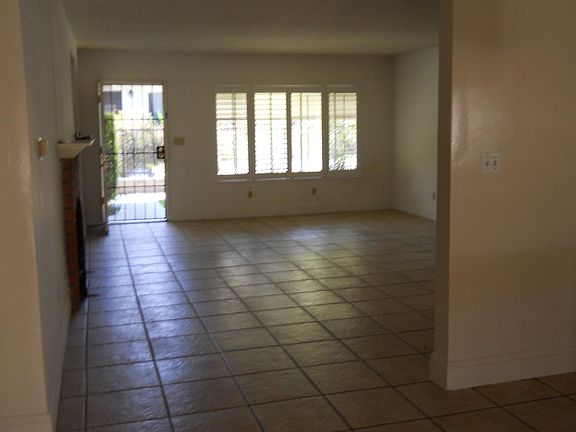 View from dining area through living room to front door. Front windows have plantation shutters.