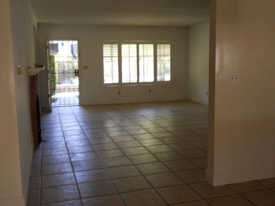 View from dining area through living room to front door. Front windows have plantation shutters.