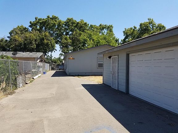 Photo taken from Back of lot. Garage accessible from alley or street and fenced all around. Door to additional bedroom and bathroom to left of roll up door.