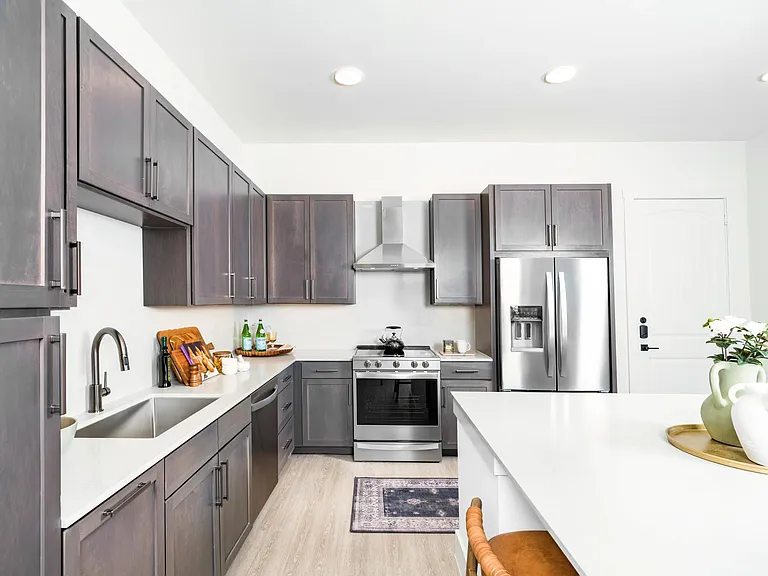 Kitchen with quartz countertops, shaker cabinetry, and stainless steel appliances arranged in a clean layout for cooking and gathering.