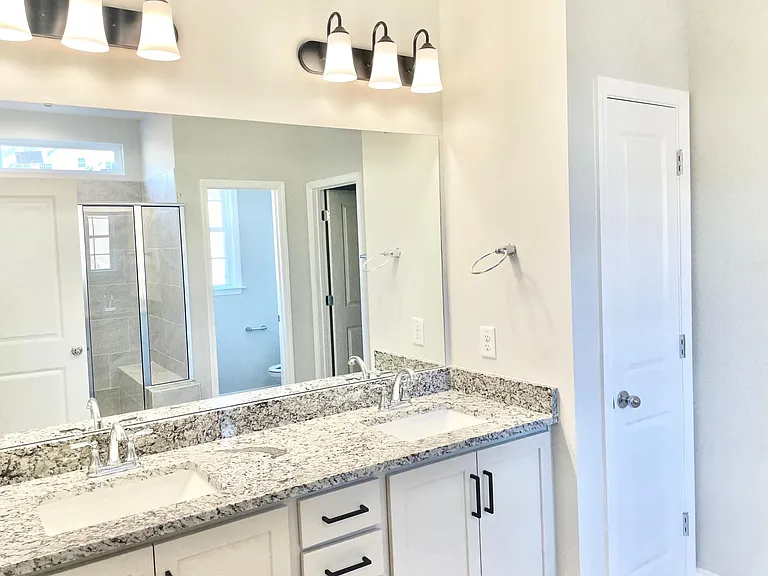 downstairs master bath includes double sink, linen closet, large walk in closet, private toilet area and walk in shower with bench seating.