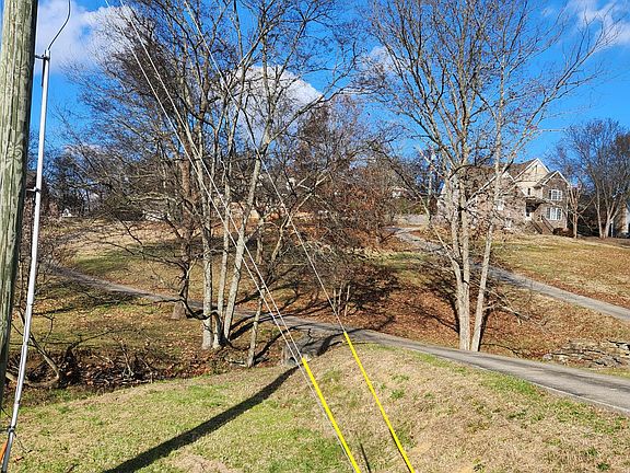 The house view from the front driveway shows how screened the tree filled front yard actually is. During the summer, the trees are a great buffer from the main road, but actually provide a lot of privacy all year.