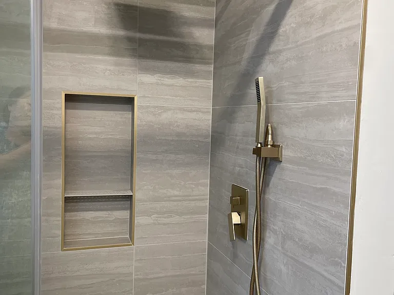 Bathroom 1 - custom-designed vanities, Delta gold hardware, large-format tile, and modern rainfall showers