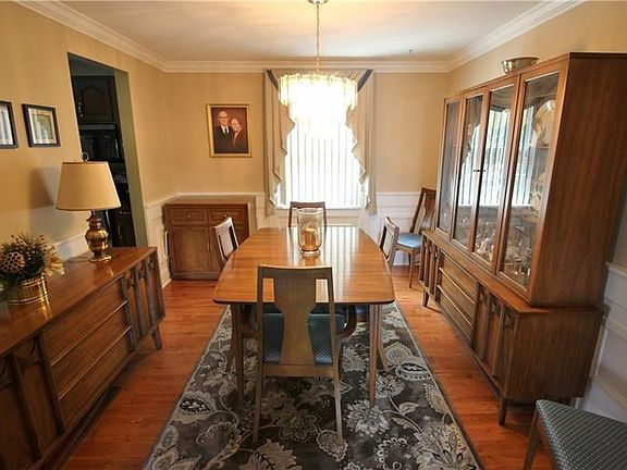 The dining room is neutral with crowne molding, wainscoting and hardwood floors