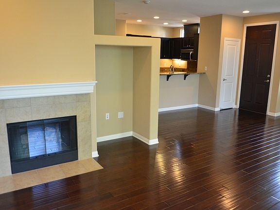 Living room, with gas fireplace, and media niche looking towards entry, coat closet, and kitchen