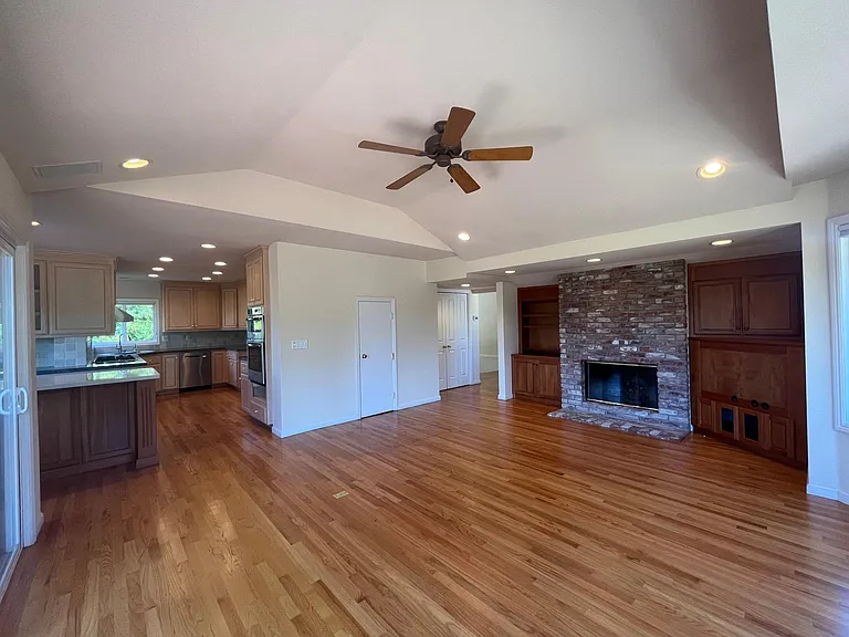 Grand family room features built-in cabinetry, vaulted ceiling, hardwood flooring, bay windows and a patio door that leads to a huge inviting outdoor deck beckoning for entertainment or relaxation.
