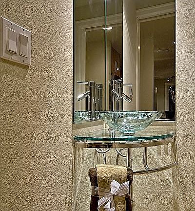 Half bath features modern glass corner mount sink.