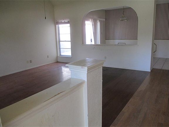 Entry way  into living room and formal dining room behind arched opening.