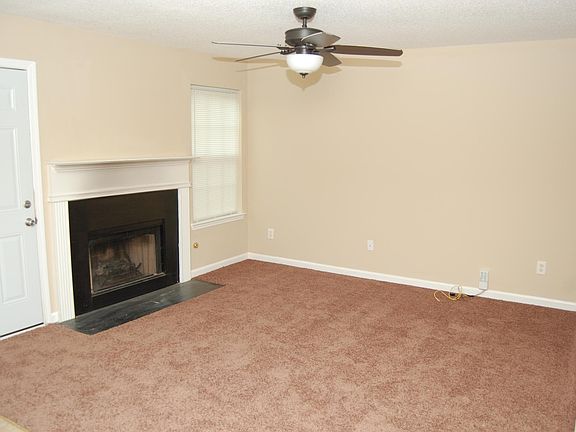 Living room with new ceiling fan and carpet as well as firep