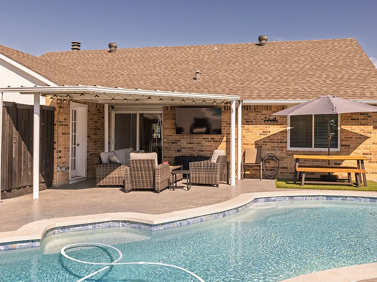 Enjoy meals al fresco on the covered outdoor patio, featuring a table, three chairs, a couch, a flat-screen Roku TV, string lights and wooden picnic table_perfect for dining in comfort while enjoying the fresh air and surrounding views.