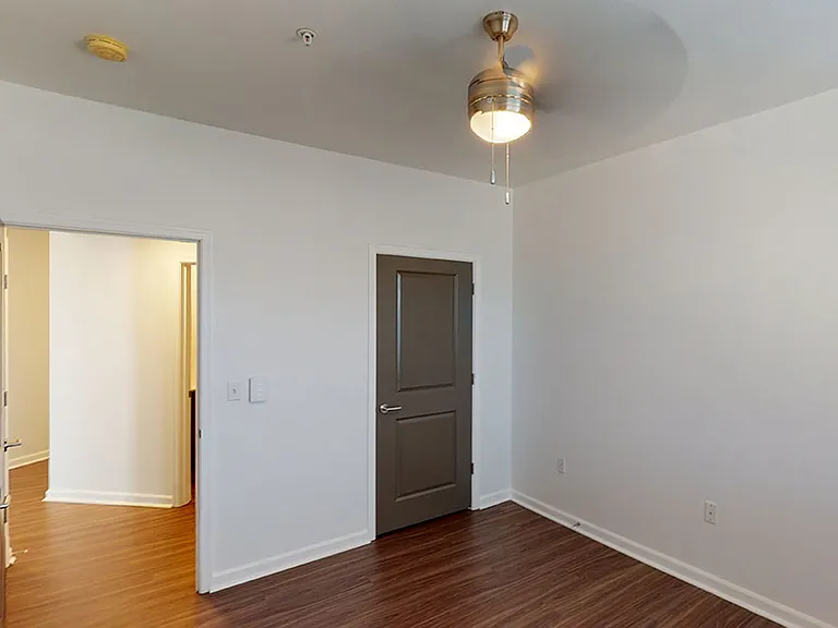 Spacious apartment bedroom with wood-style flooring.