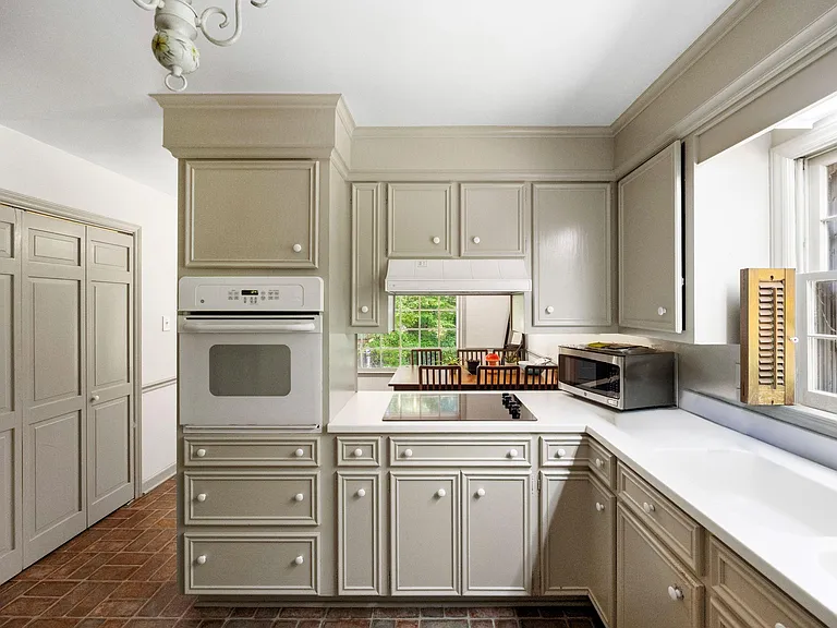 U-shaped kitchen with abundant cabinet storage, long counters, wall oven, and a large window overlooking the yard.