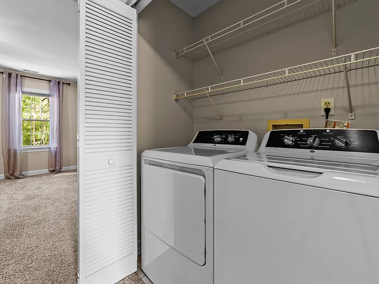 Convenient laundry area with washer, dryer, and storage shelving.