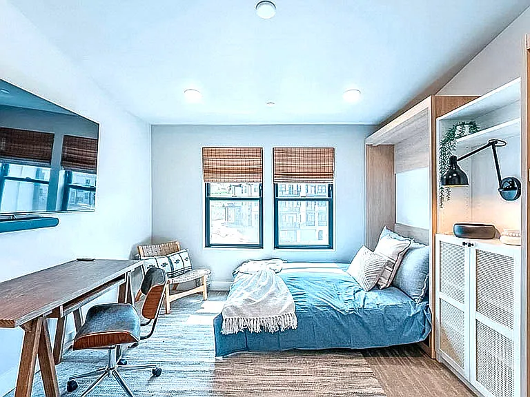 Versatile bedroom with built-in Murphy bed, dedicated desk workspace, and bamboo blinds _ ideal as a guest room or home office