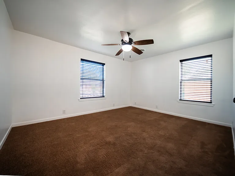 Comfortable bedroom with ceiling fan, plush carpet, and window blinds