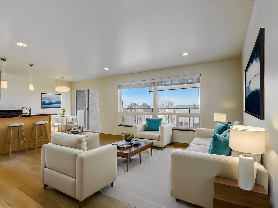A spacious living room featuring comfortable sofas, a stylish coffee table, and a view of the kitchen, creating a seamless and inviting living space.