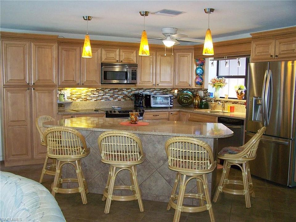 View of updated kitchen with Stainless appliances, Quartz counters, Customs lighting, large neutral tile flooring on diagonal.