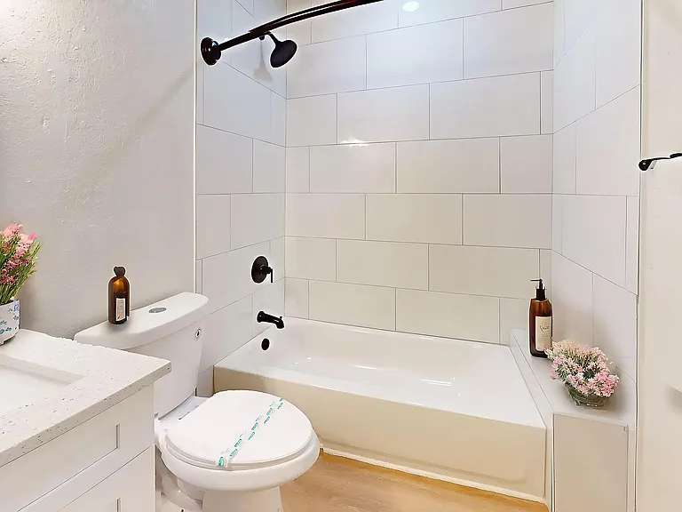 Bright, modern bathroom with sleek white tiles, elegant fixtures, and fresh floral accents.