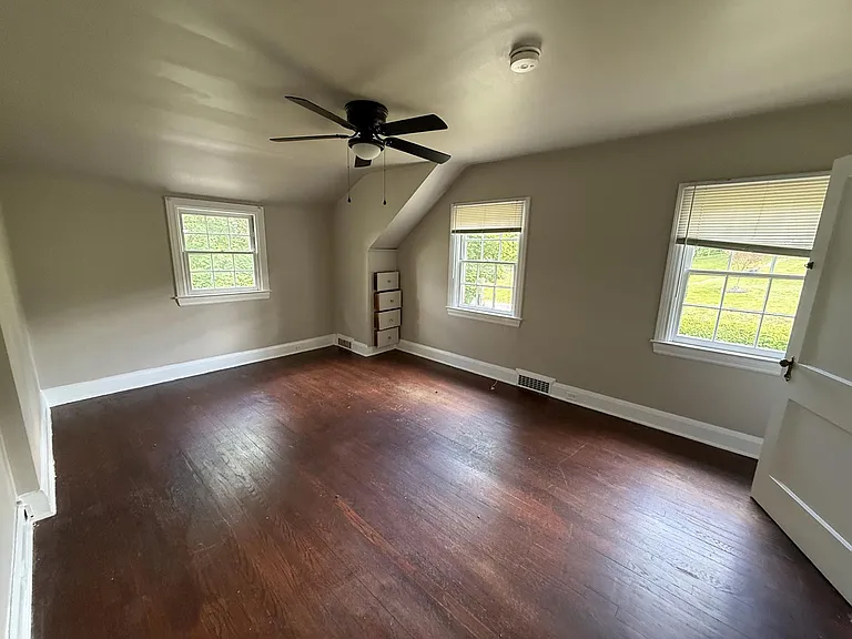Front bedroom with original hardwood floors, a closet and ceiling fan. Window AC.