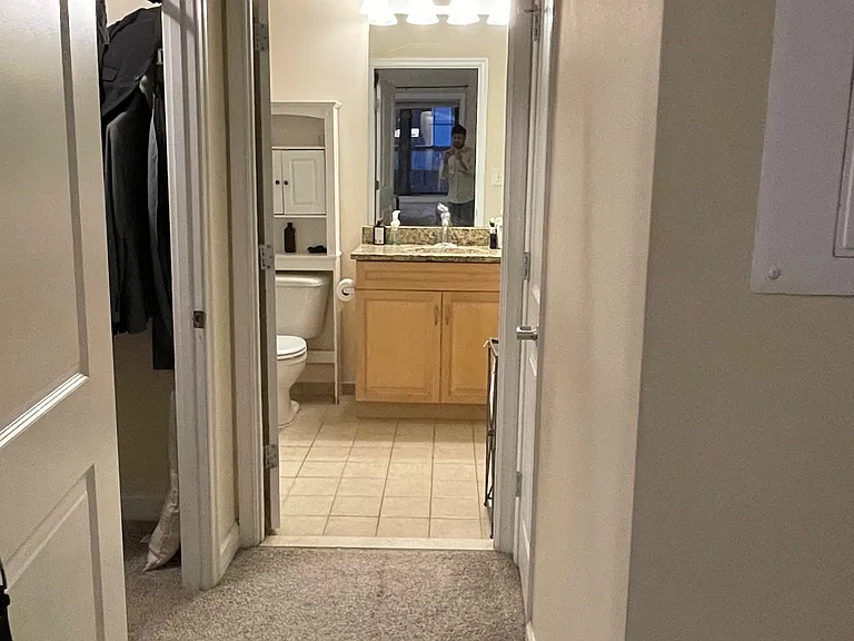 View from the bedroom to the bathroom, with the walk-in linen closet to the left (with a door) and another closet to the right