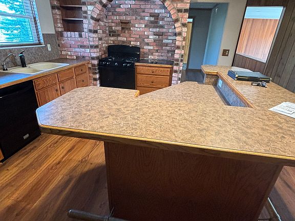 Kitchen with island bar and brick cooking area with GE gas range and Jennaire electric cooktop