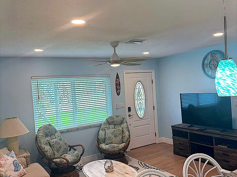 Inviting living area with ample seating, large window with blinds, and a media consoleideal for relaxing or entertaining.