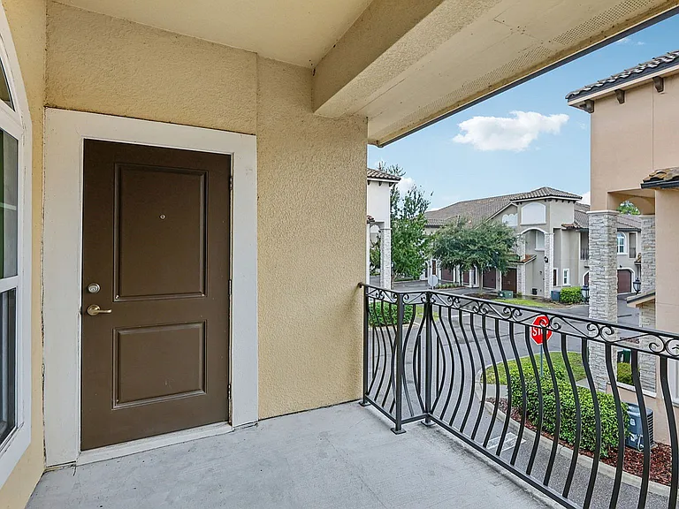Inviting apartment entrance with elegant wrought-iron railing and charming neighborhood view.