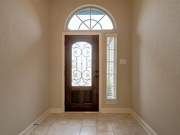 Foyer features tile flooring with crown molding and high ceilings.
