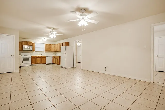Kitchen/Living room area with ceiling fans, entrance to both bedrooms on the right/ a Coat Closet on t