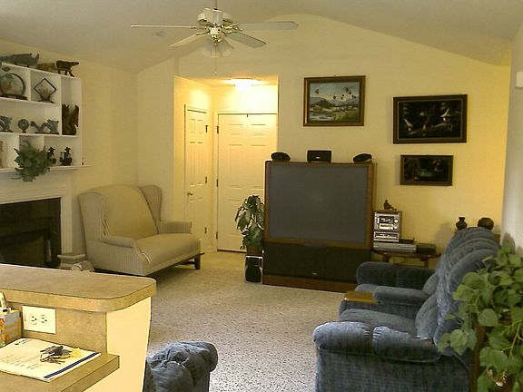 Great room with vaulted ceiling, fire place and built-in shelving above it.