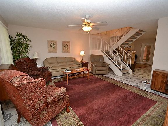 Living room accented by tile flooring, ceiling fan with light fixture and a walk-in closet.