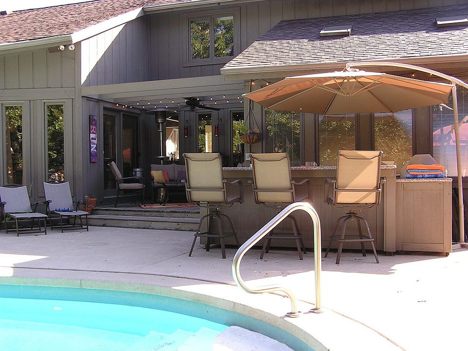 Outdoor kitchen with two-level granite countertops, built-in stainless grill.