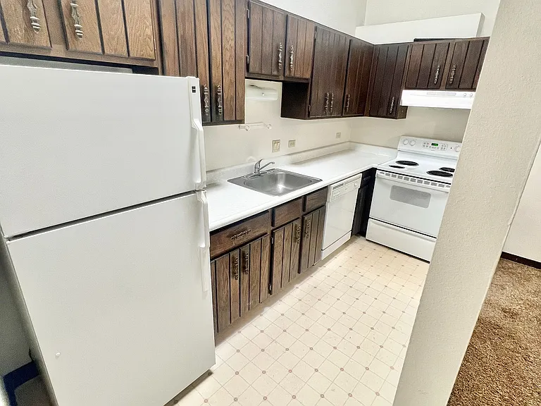 Charming kitchen with vintage wooden cabinets, sleek white appliances, and stylish pendant lighting creating a welcoming atmosphere.